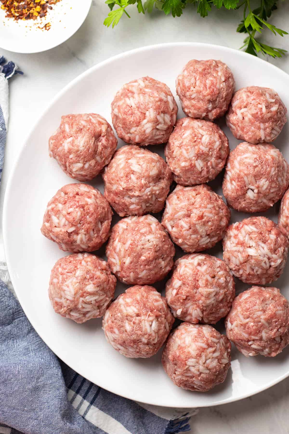 Uncooked meatballs with rice on a plate.