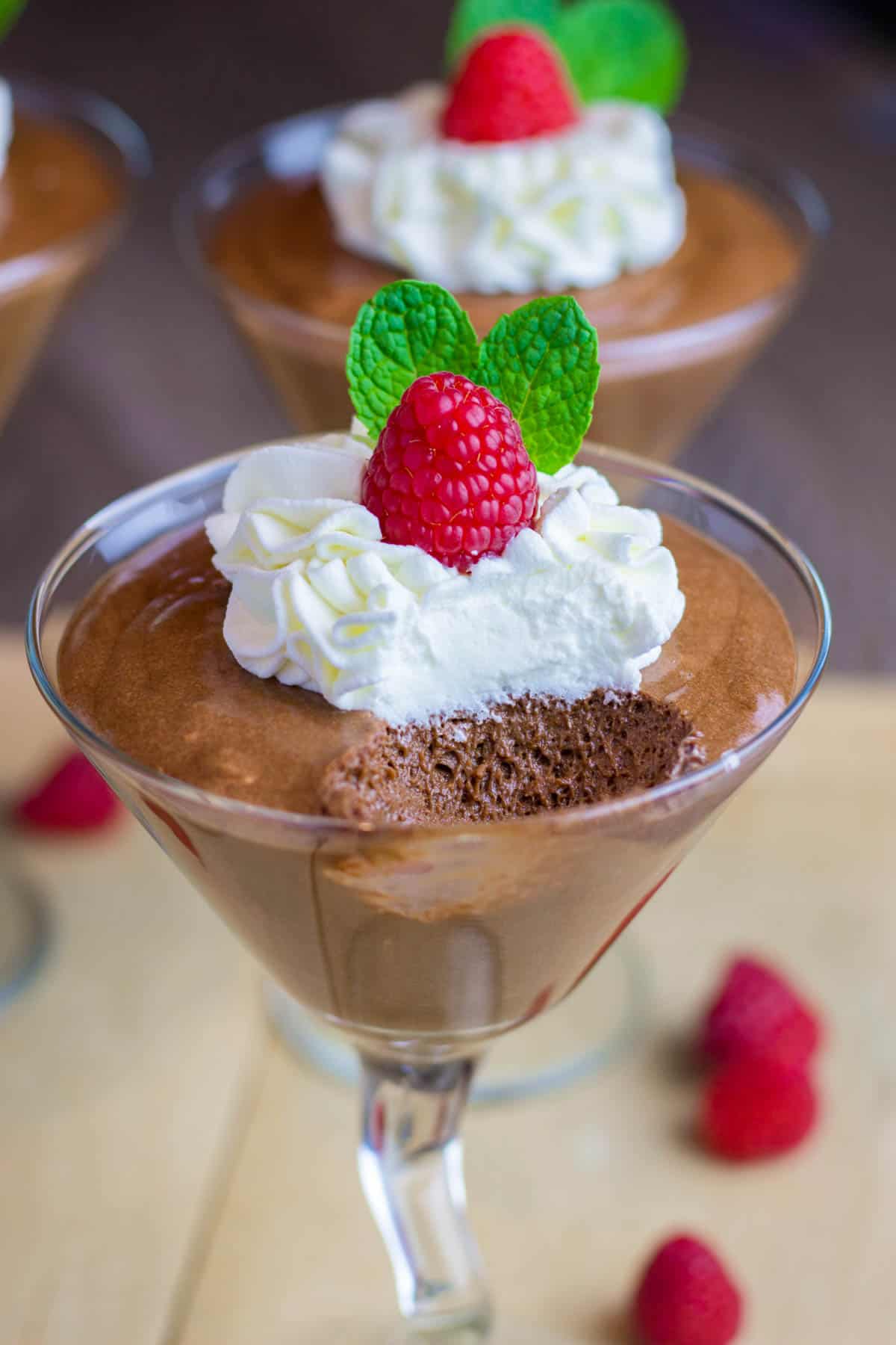 Chocolate mousse, topped with whipped cream, raspberry, and mint leaves.
