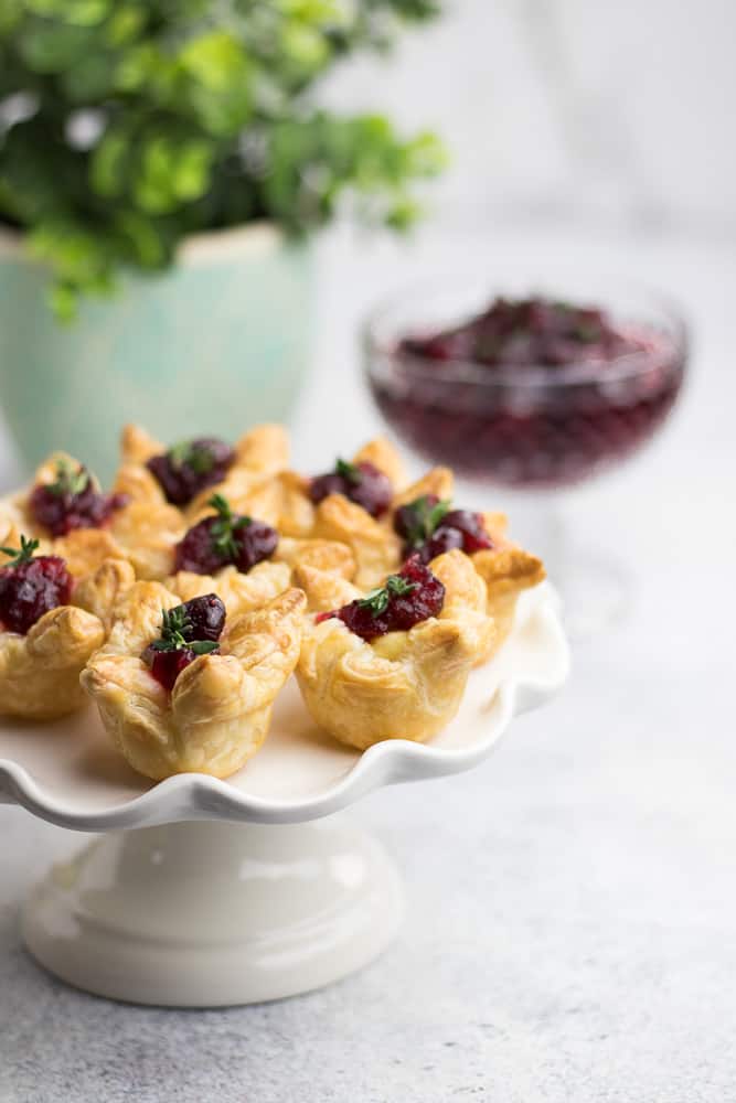 3 Ingredient Cranberry Bites is an easy appetizer for a party. Made with Puff Pastry, Brie Cheese, and Cranberry Sauce, this lovely starter will be perfect for the Holiday Season!