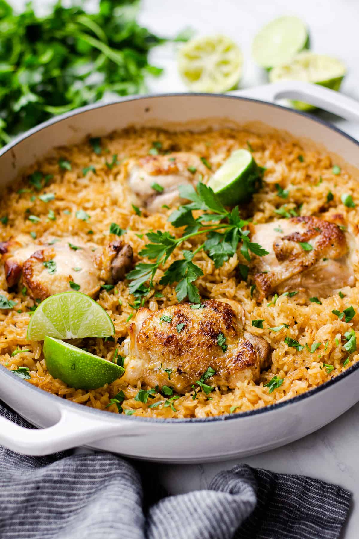 chicken with rice, cooked in white pan, and topped with parsley and lime.