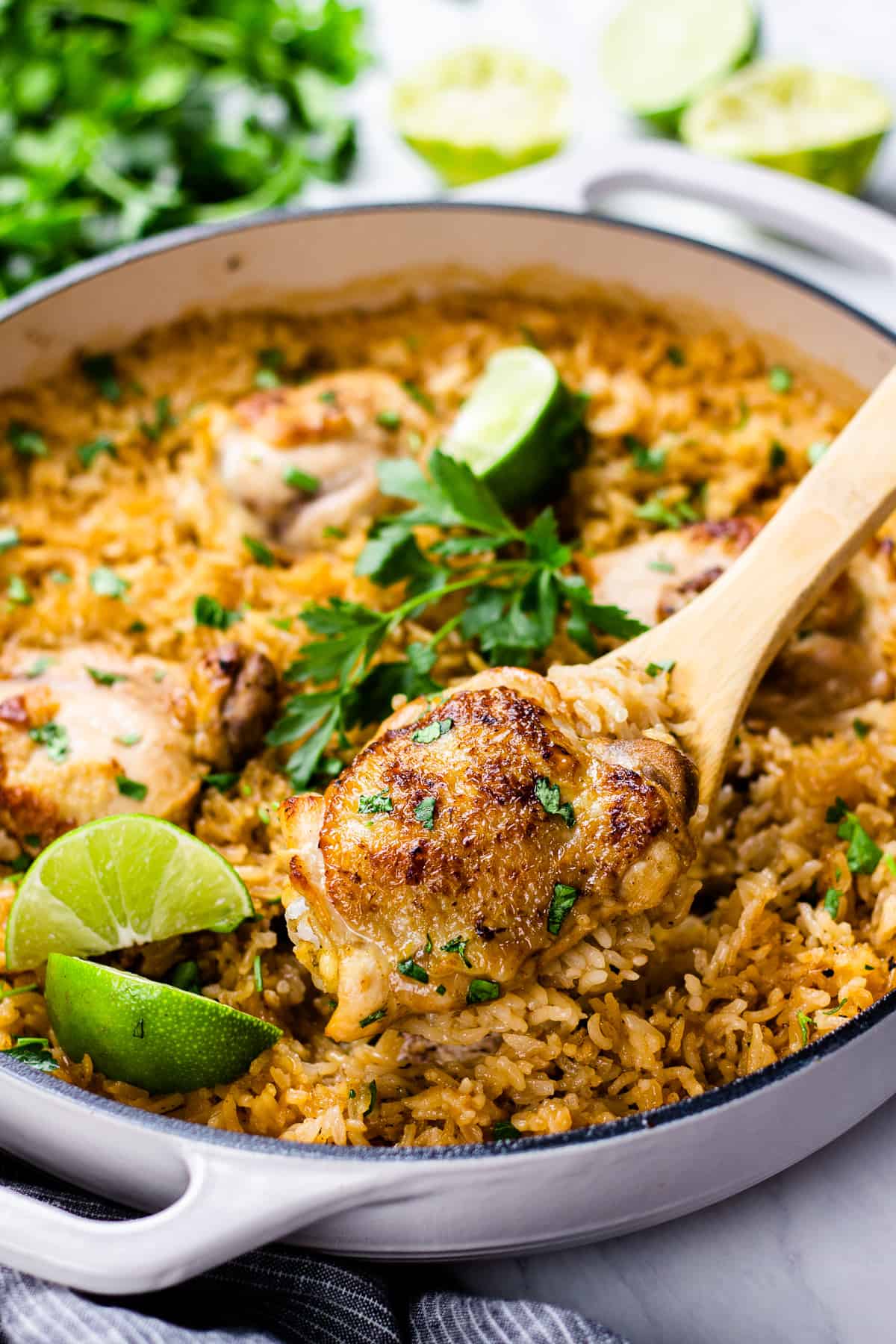 chicken with rice, cooked in white pan, and topped with parsley and lime.