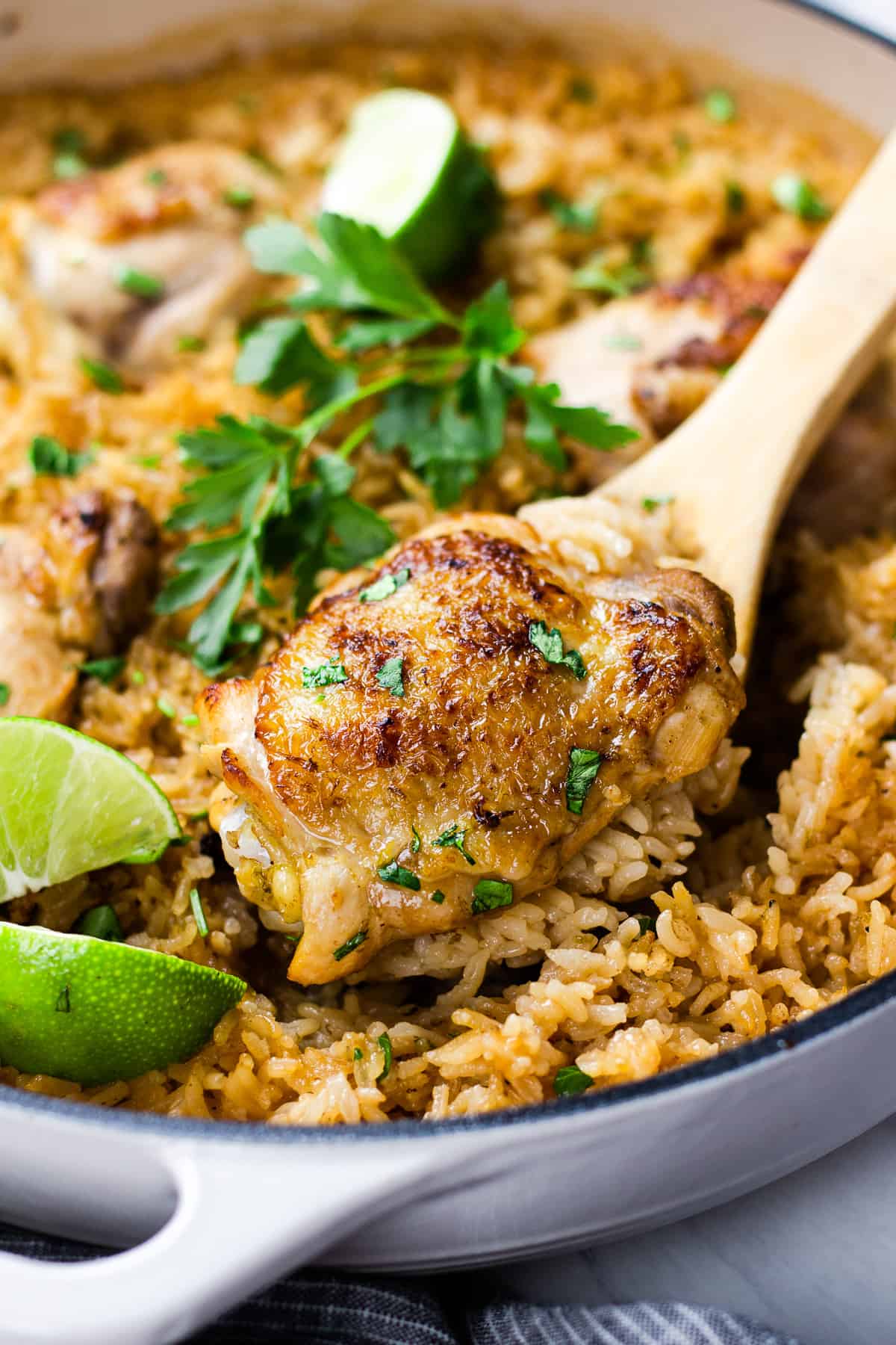 A close up photo of chicken with rice, cooked in white pan.