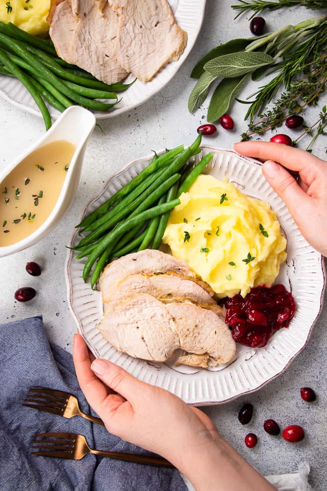 Oven Roasted Turkey Breast, mashed potaotes, green beans, and cranberry sauce on a white plate.