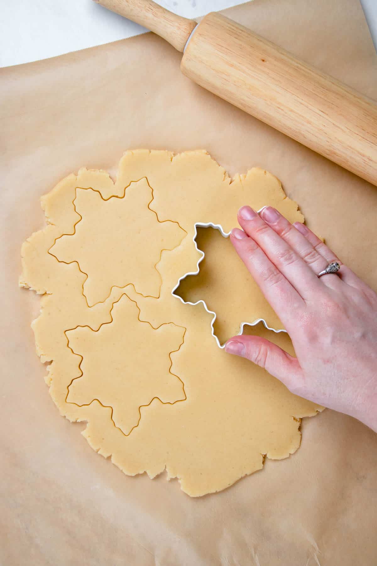 Process photos of cutting out cookies on a rolled dough.