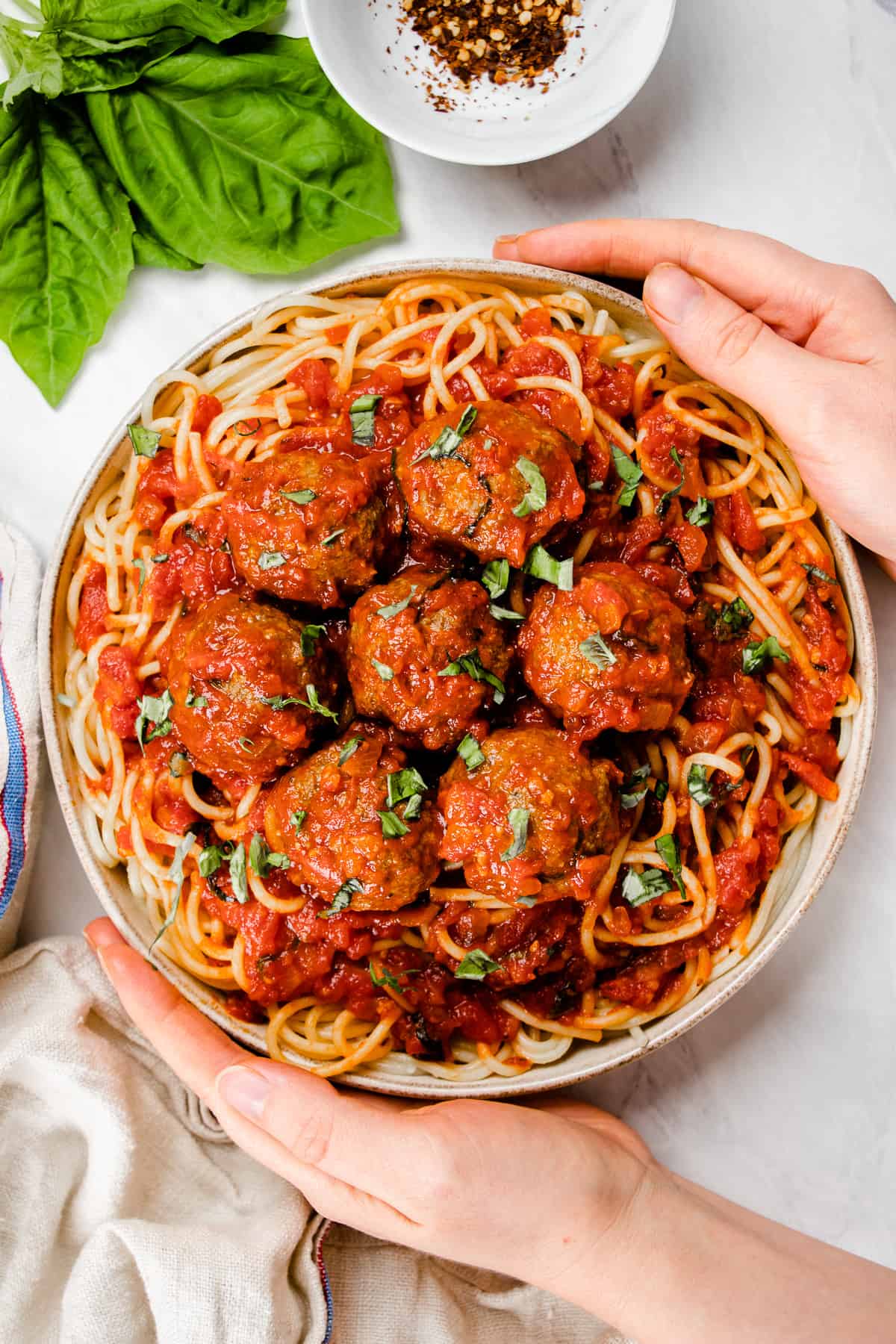 meatballs mixed with marinara sauce on top of the spaghetti are served on a plate.