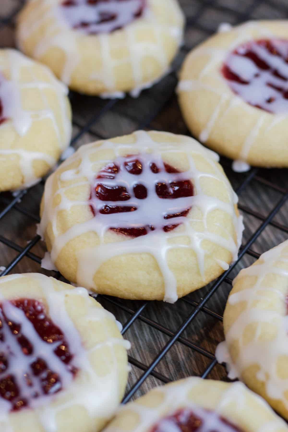 Thumbprint Cookies, filled with rasbeey jam on a wire rack.