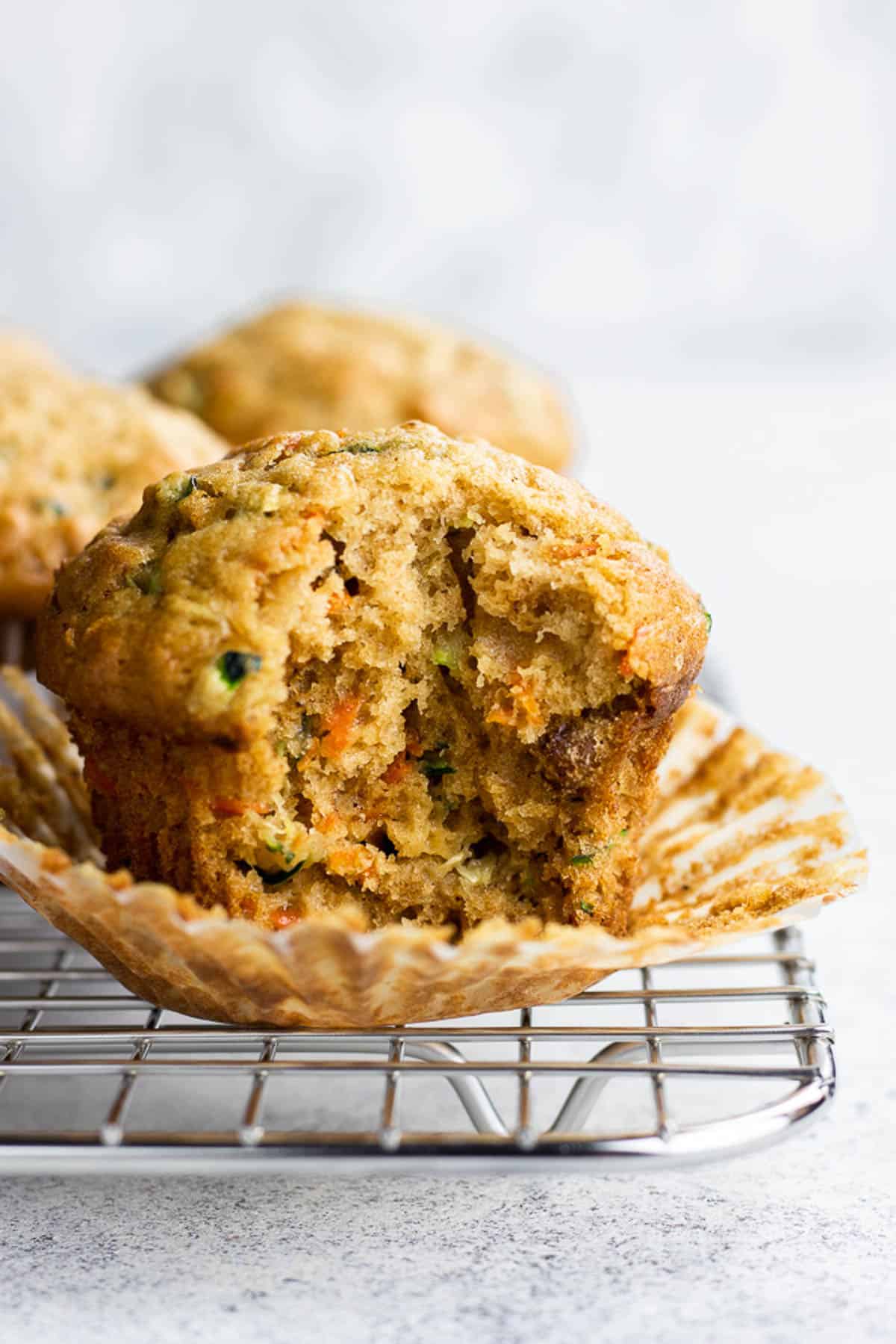 A bite shot of carrot zucchini muffin on a wire rack.