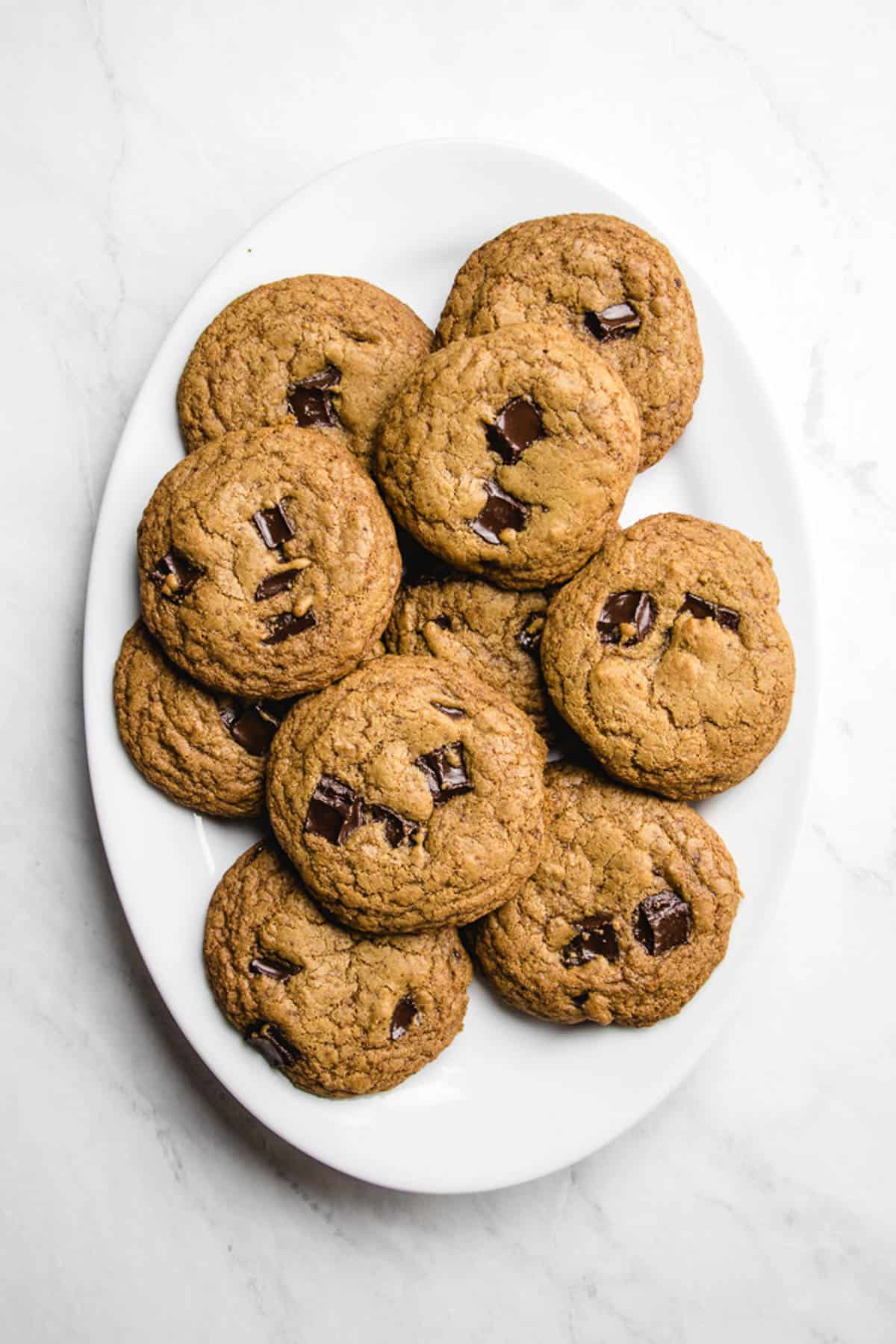 Chocolate chip cookies on a white oval plate.