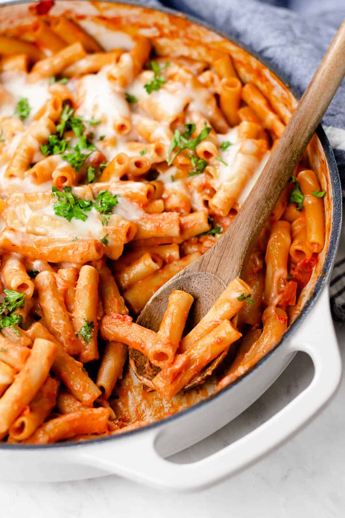 Cheesy baked ziti in a white casserole pan.