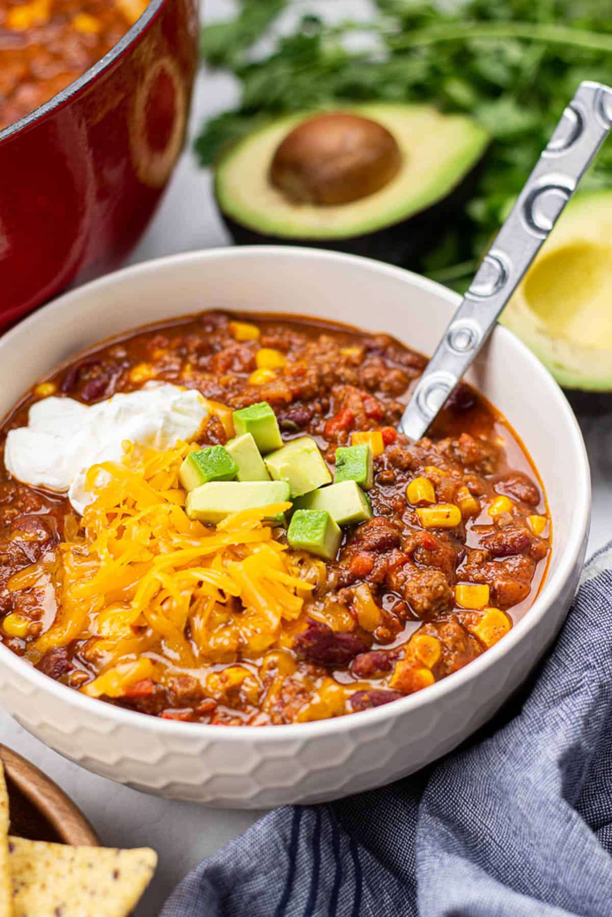 beef chilli, topped with sour cream, cheese, and avocado in a bowl.