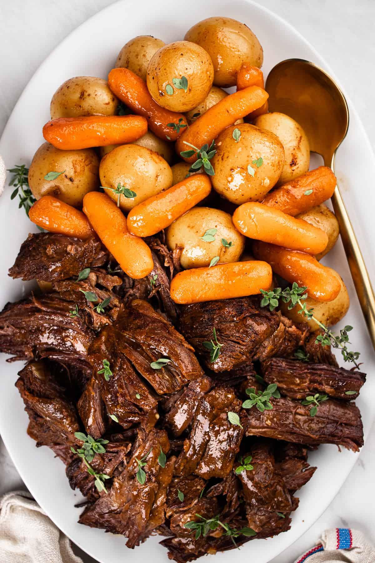 Pot Roast with potatoes and carrots served on a white plate.