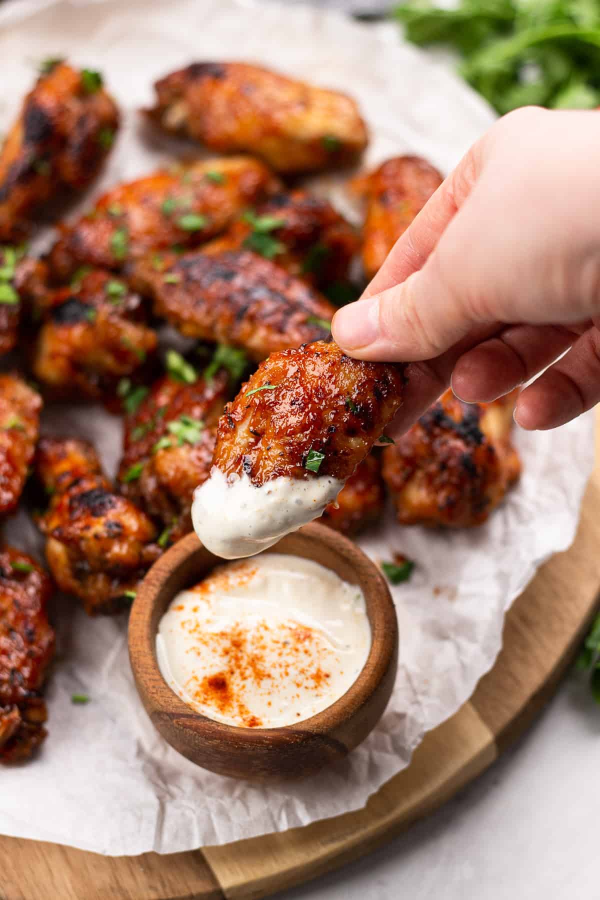 Dipping BBQ chicken wing in a ranch sauce.