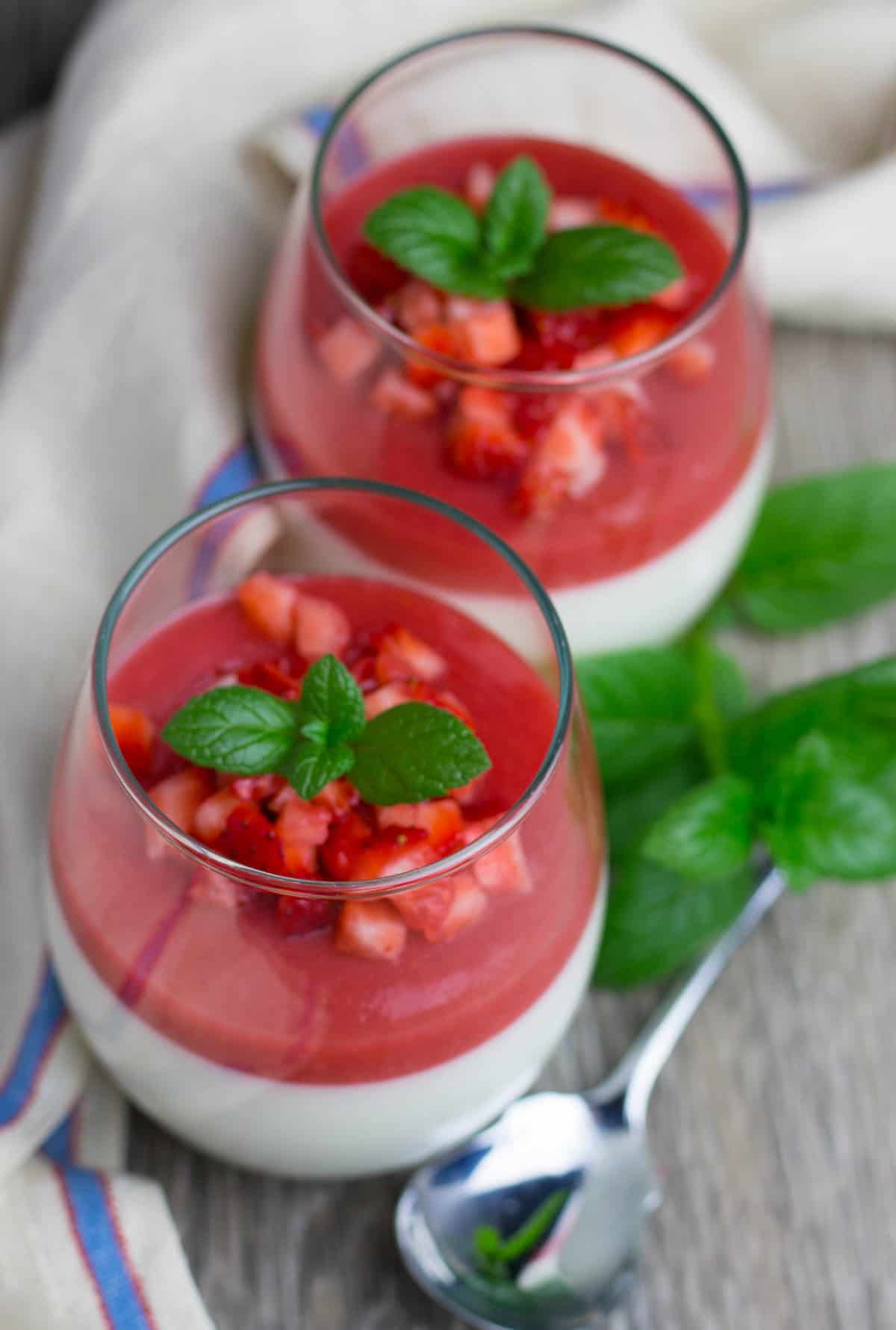 Panna Cotta in cups, topped with strawberry sauce.