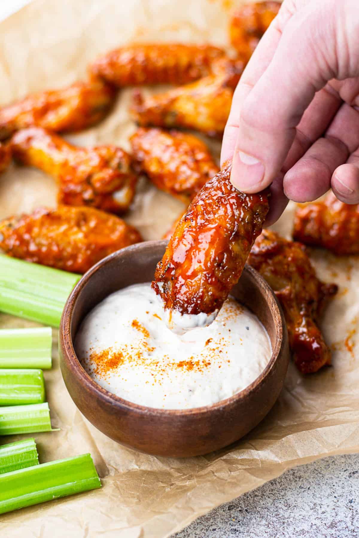 Diping a chicken wing in a ranch sauce.