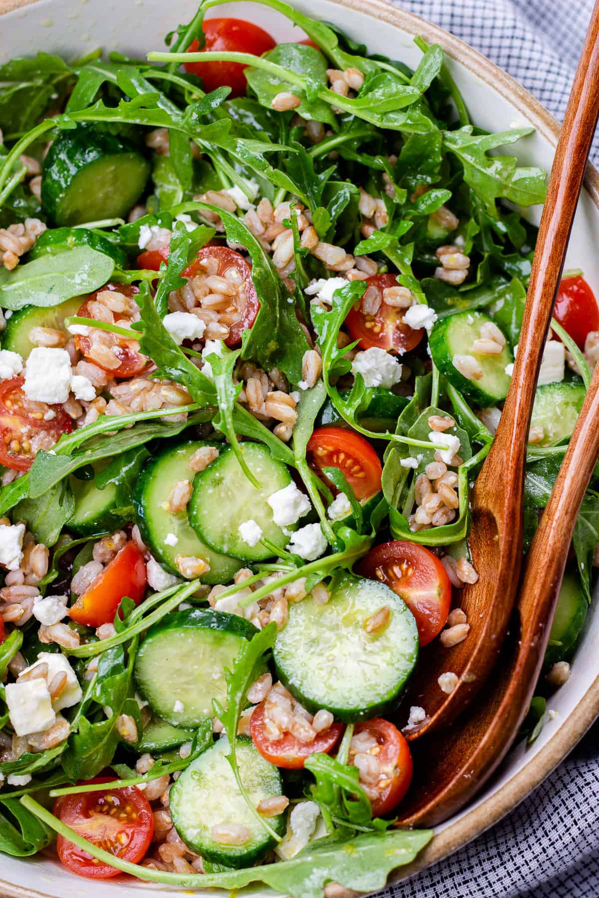 Farro salad with arugula, cucumbers, and tomatoes in a bowl.