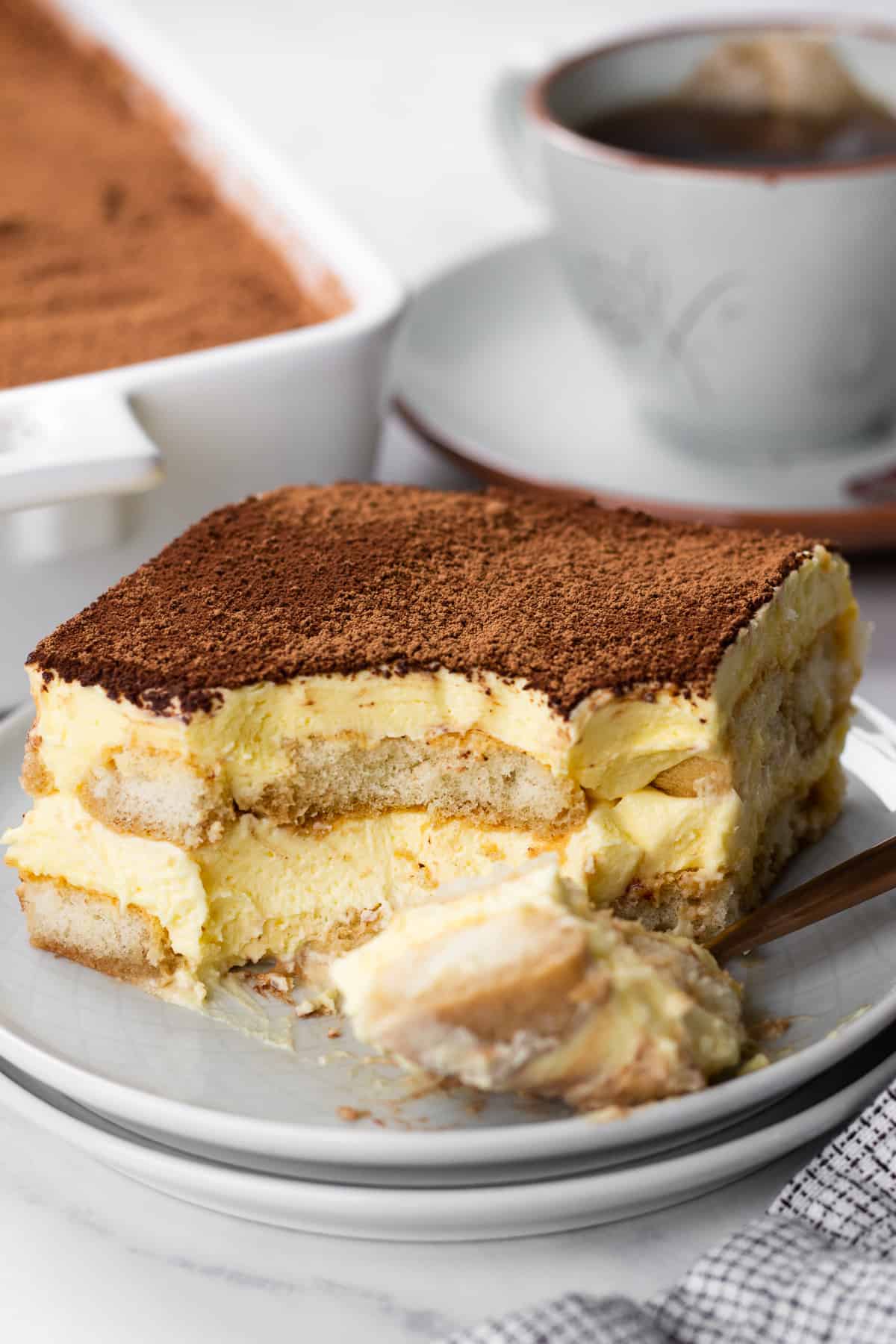 A slice of Tiramisu on a grey plate.