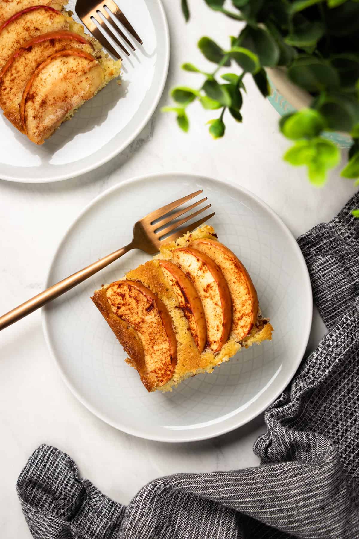 A slice of apple cake on a small grey plate with a fork.