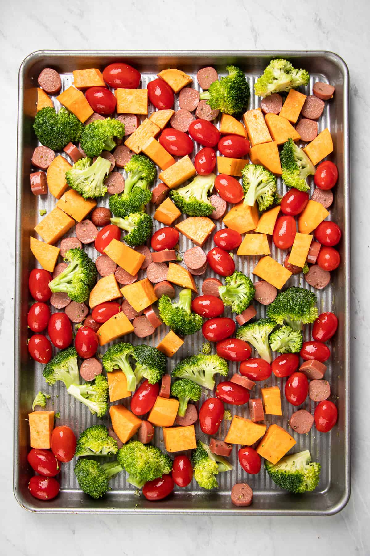 Chopped vegetables with sausage on a sheet pan.