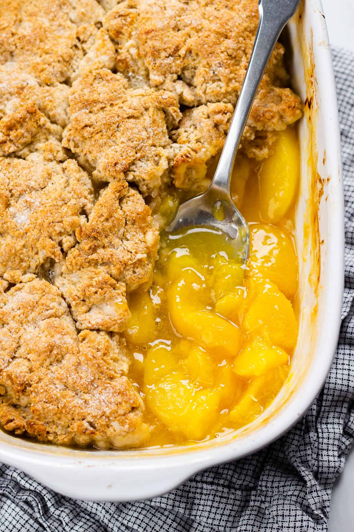 Scooped Peach cobbler in a white baking dish.