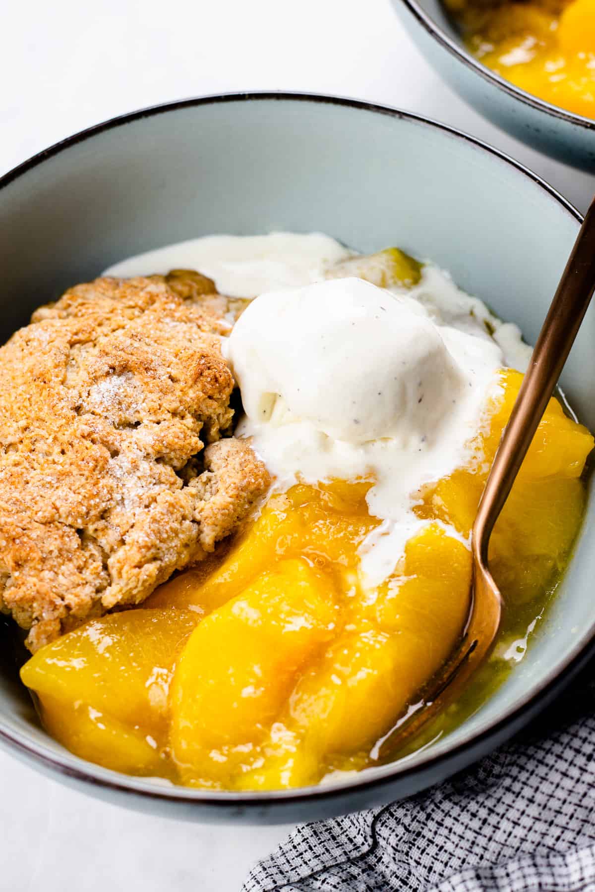 Peach Cobbler with a scoop of ice cream in a blue bowl.