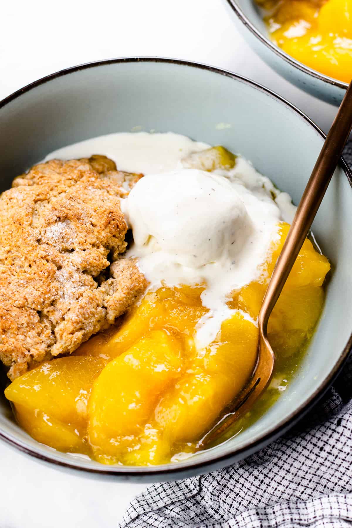 Peach Cobbler with a scoop of ice cream in a blue bowl.