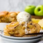 A slice of an Apple Pie wiht a scoop of ice cream on top.