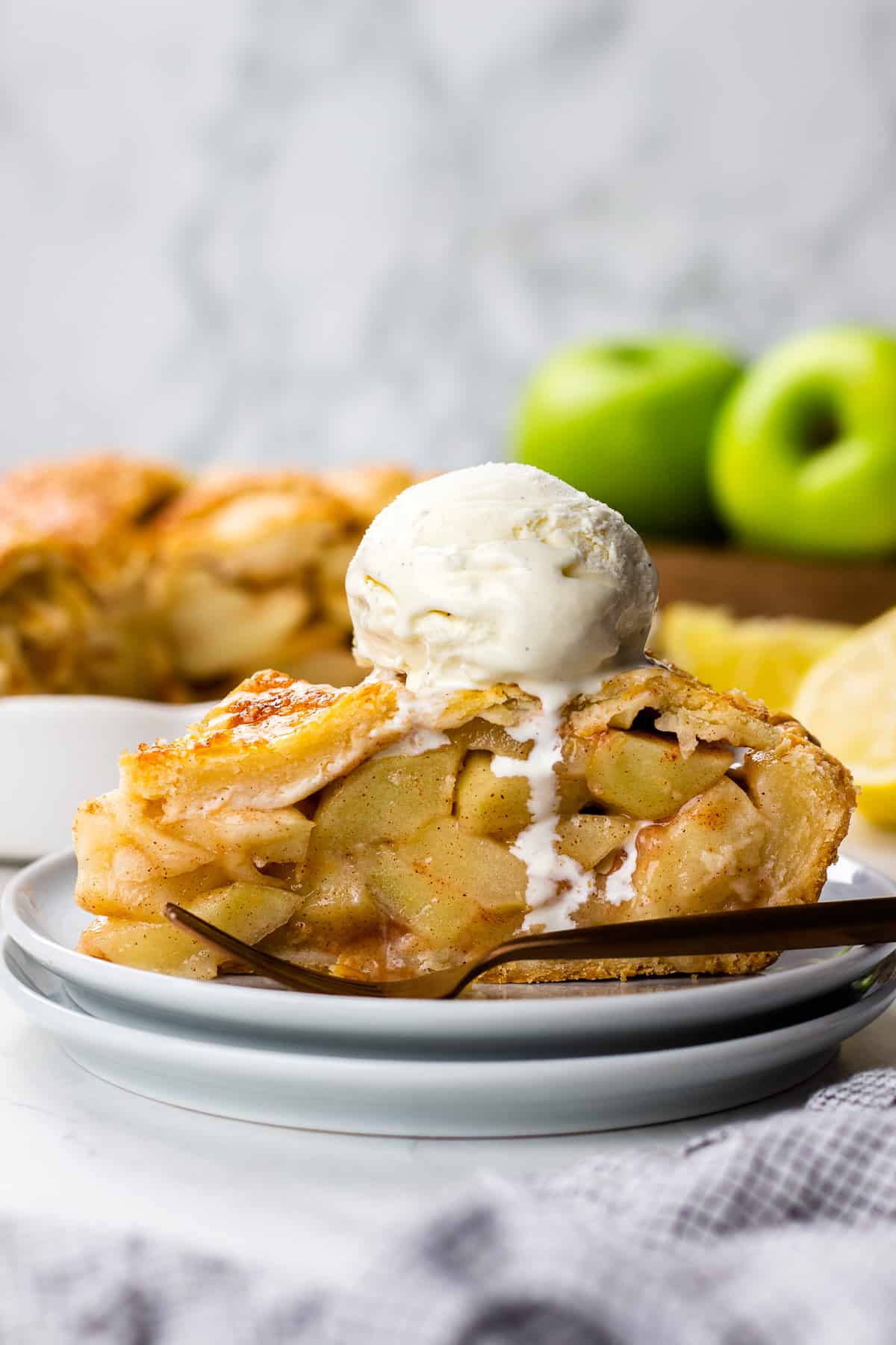 A slice of an Apple Pie wiht a scoop of ice cream on top.