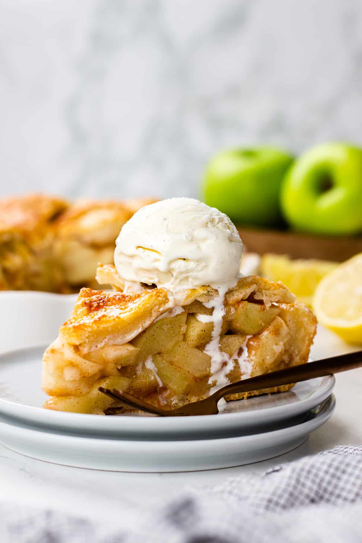 A slice of an Apple Pie wiht a scoop of ice cream on top.