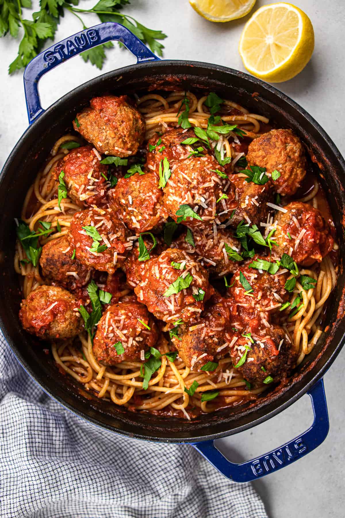 Spaghetti with meatballs, topped with parmesan and chopped parsley, in Dutch Oven.