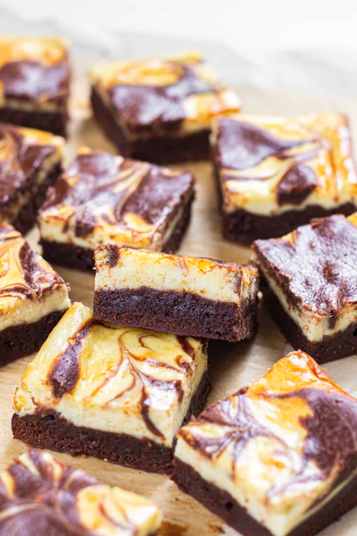 Cheesecake brownies, cut in small squares, laying on a parchment paper.