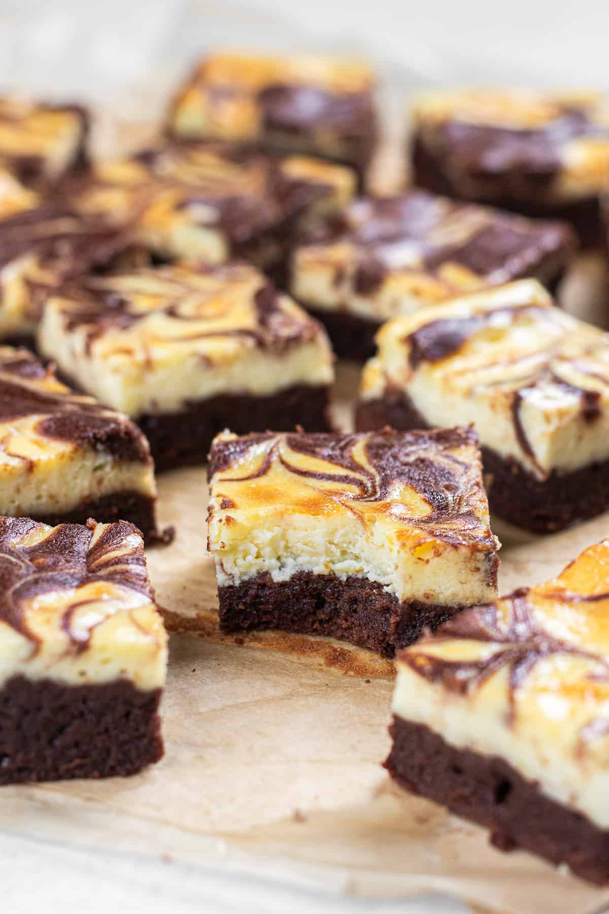 A bite shot of Cheesecake brownies laying on a parchment paper.