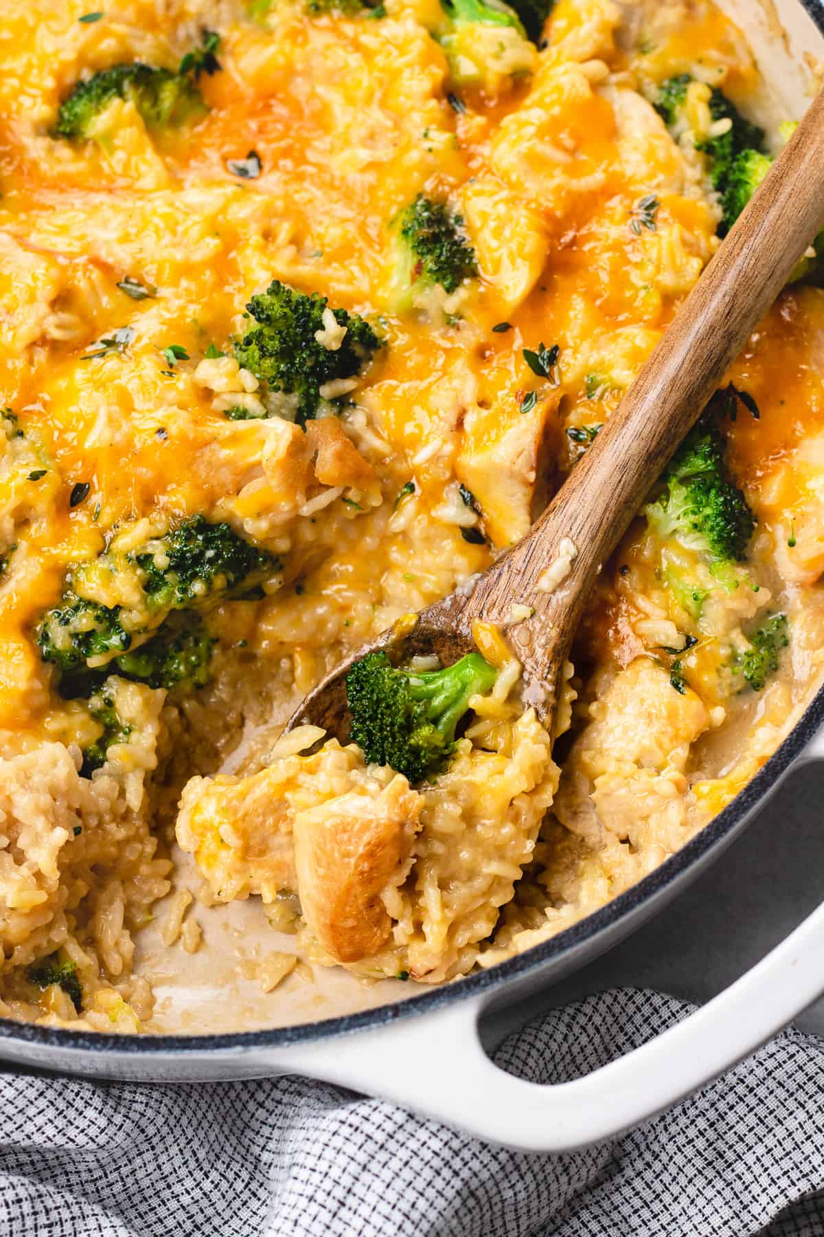 Chicken and rice with broccoli and melted cheese in a white casserole.