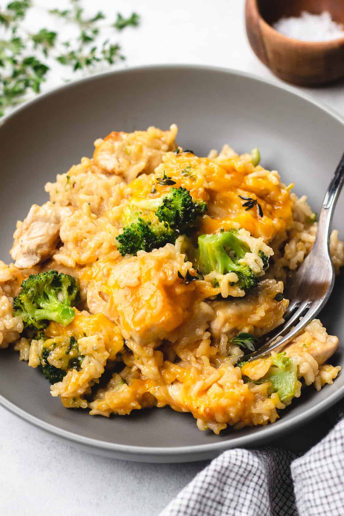 Chicken and rice with broccoli and melted cheese in a grey bowl.
