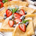 Folded crepes, topped with berries and powdered sugar.