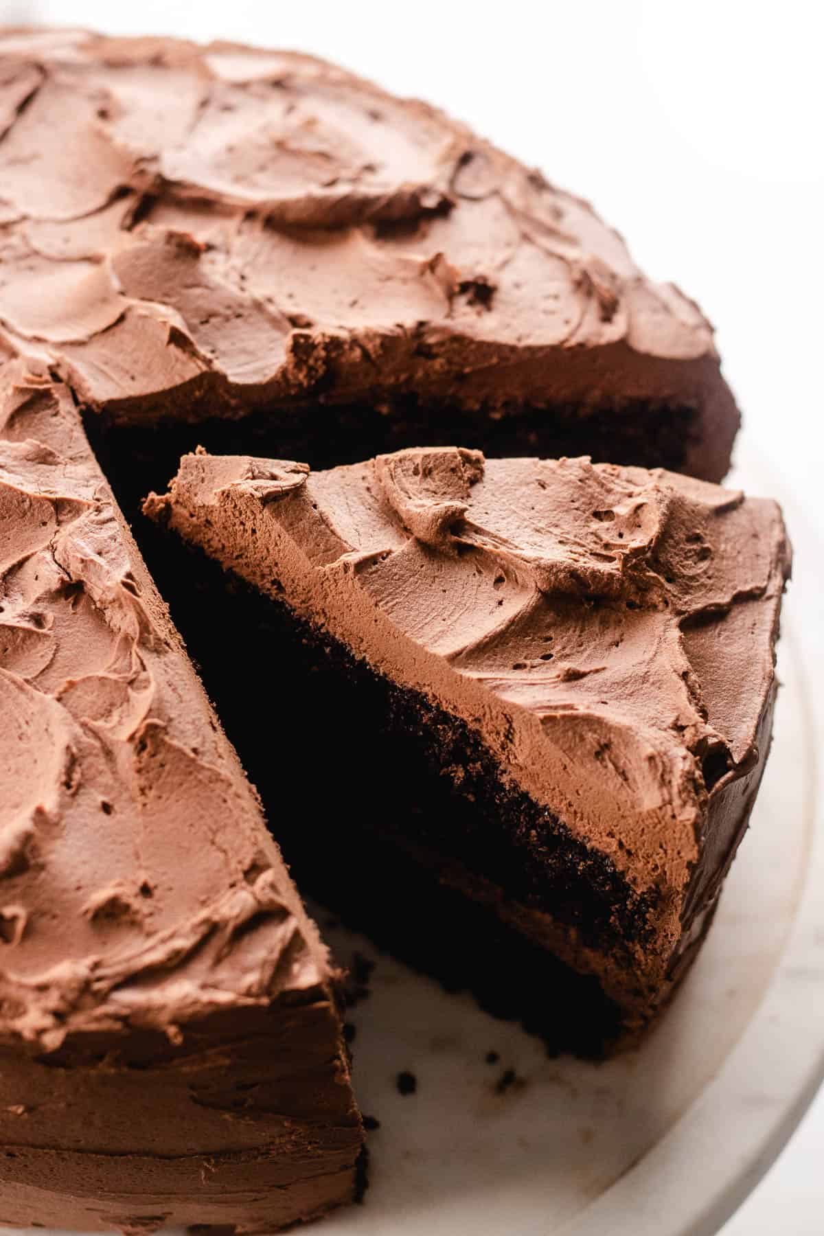 A precut chocolate cake on a platter.