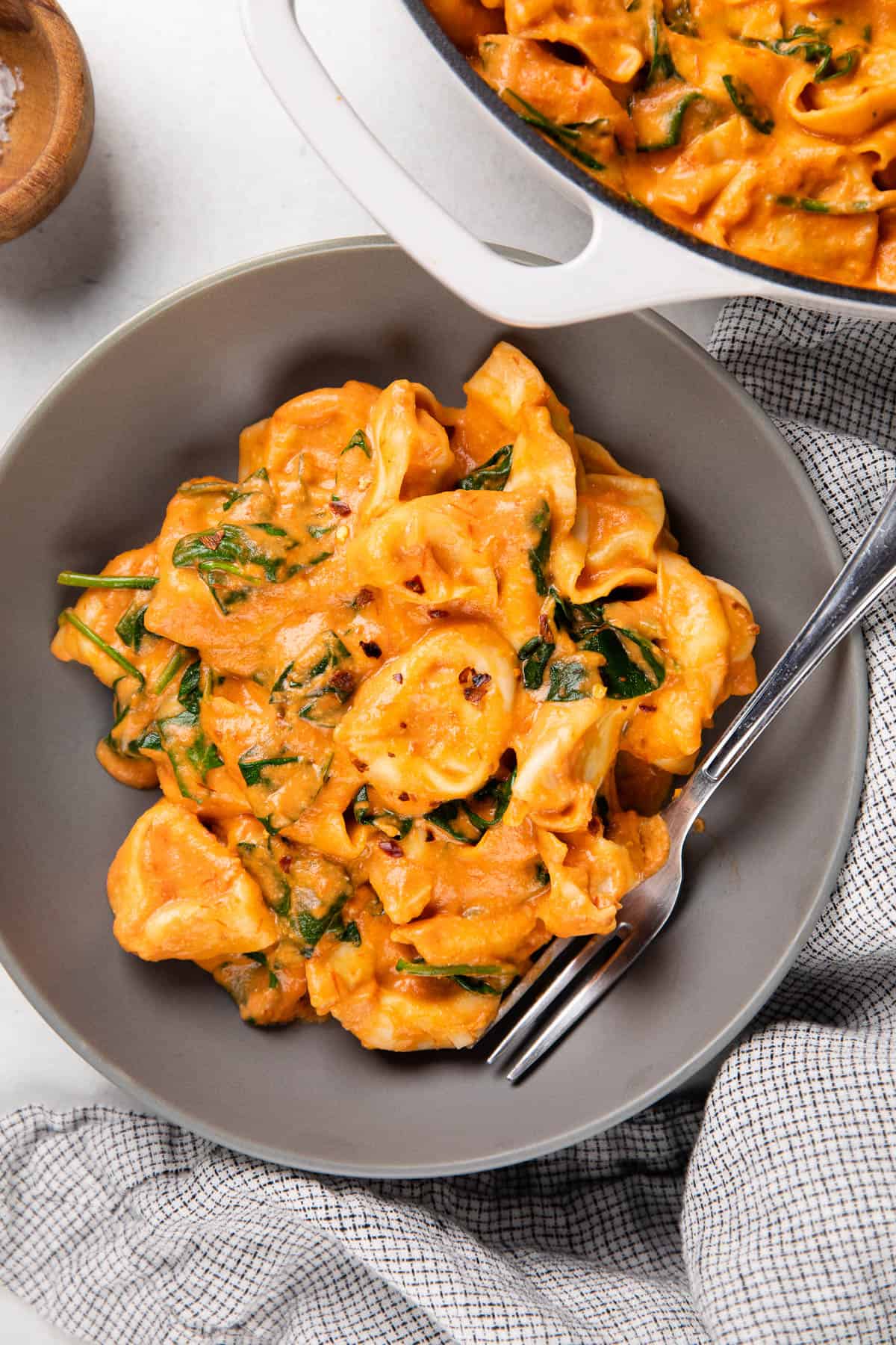 Tortellini in creamy tomato sauce in a grey bowl with a fork.
