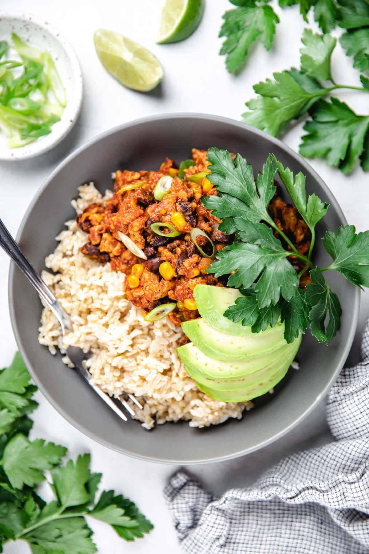 Turkey taco skillet with brown rice, topped with avocado and cilantro.