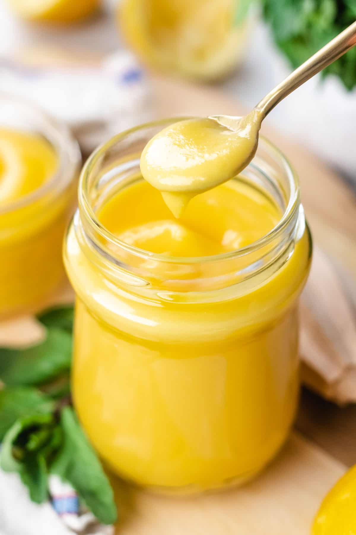 Lemon curd in a jar on a cutting board.