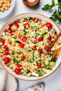 Salad with orzo, cucumbers, cherry tomatoes in a large bowl.