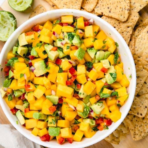 Mango Avocado Salsa with tortilla chips on a cutting board.