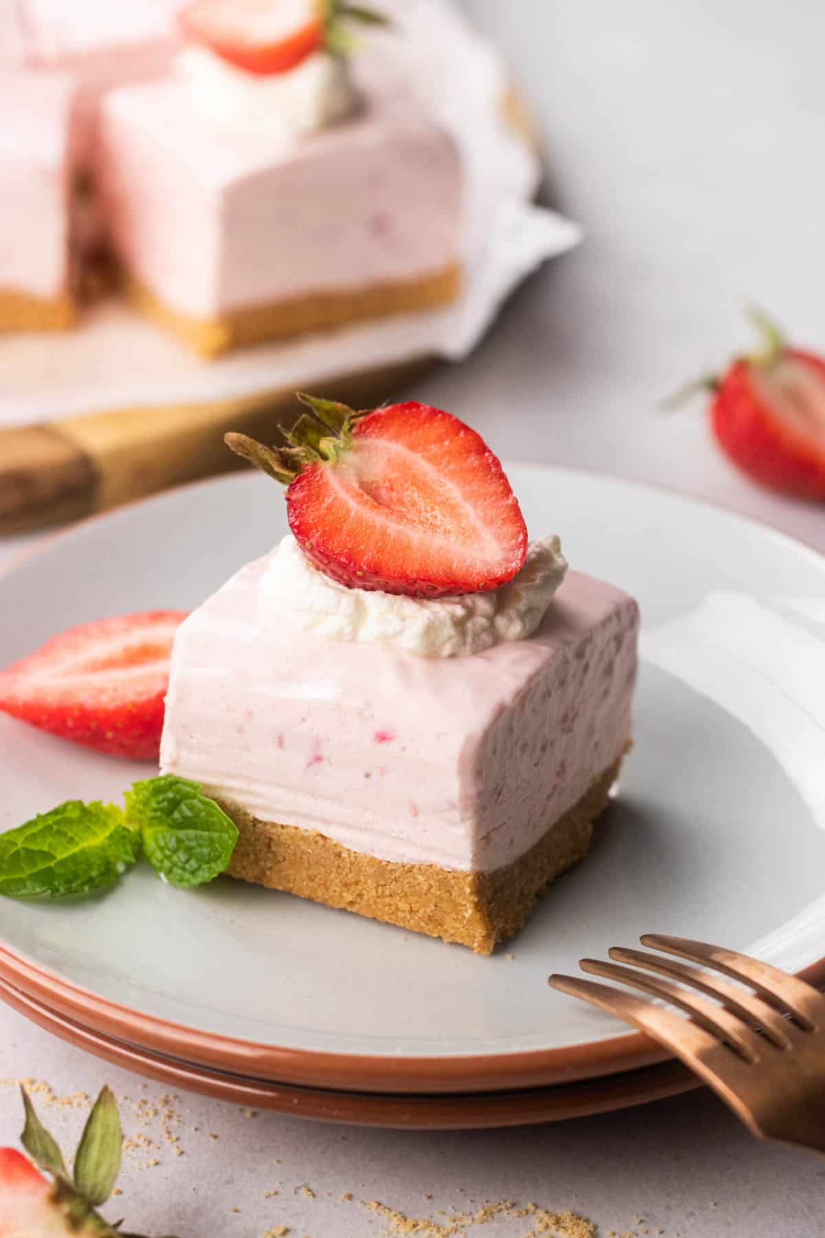 Strawberry cheesecake bar, topped with whipped cream and a strawberry.