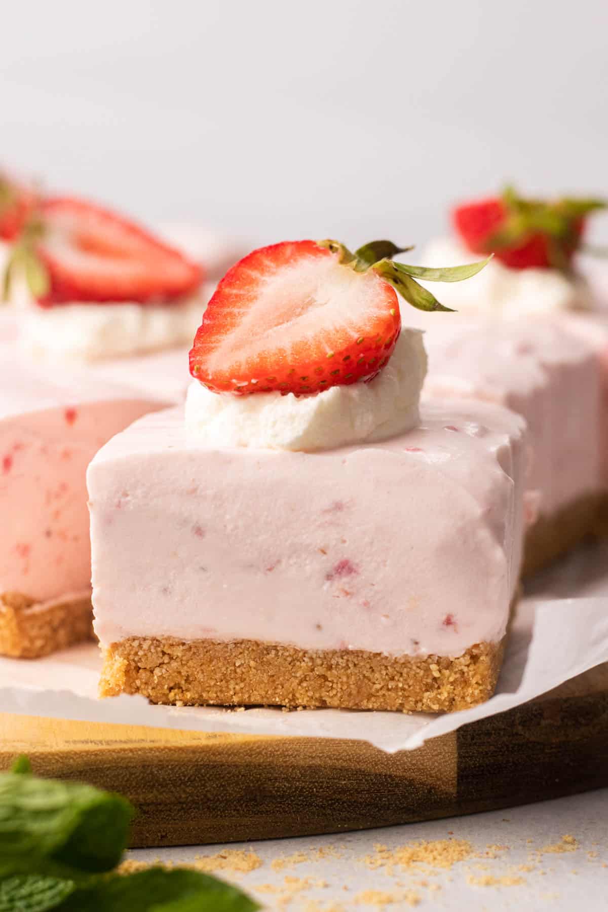 Strawberry cheesecake bar, topped with whipped cream and a strawberry.