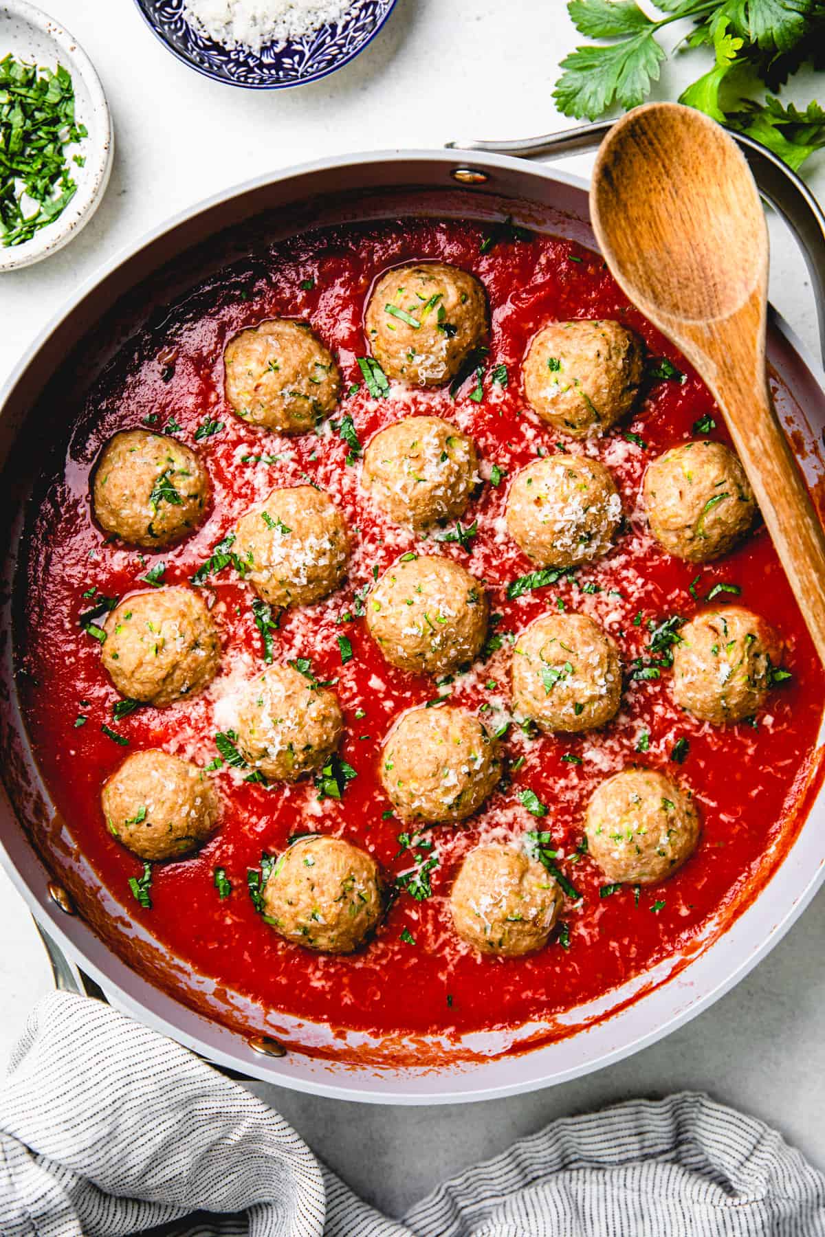 Turkey Zucchini Meatballs with Marinara Sauce in a large skillet with a wooden spoon.