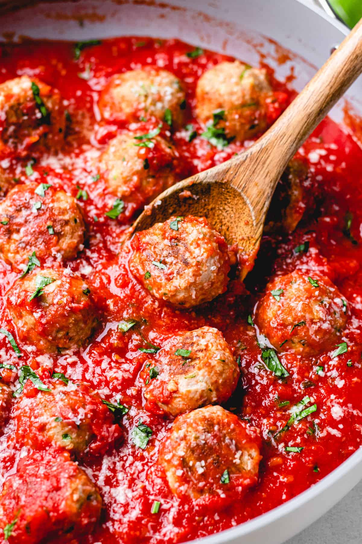 Turkey Zucchini Meatballs with Marinara Sauce in a large skillet with a wooden spoon.