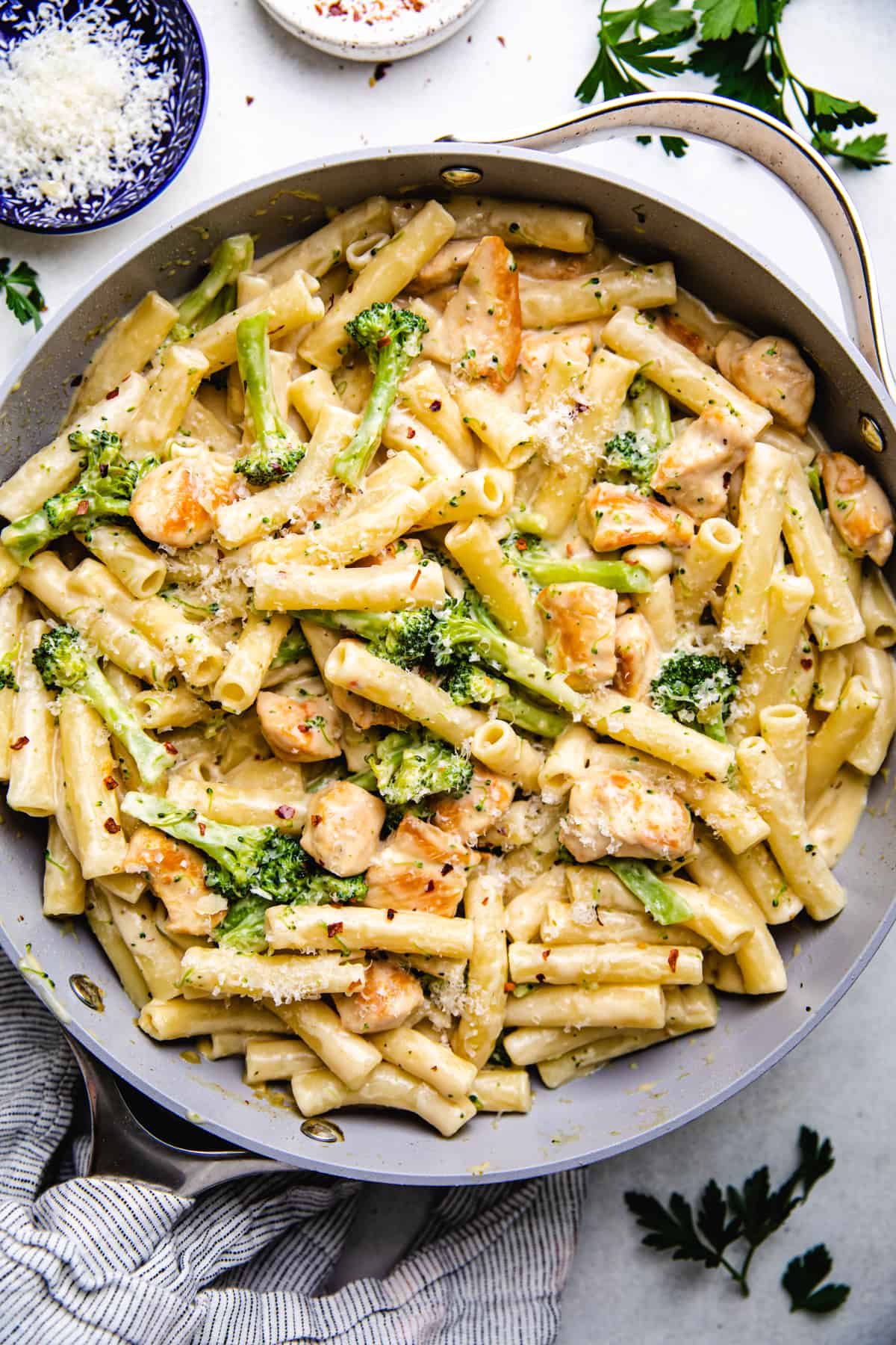 Pasta, diced chicken, and broccolli in creamy sauce in a skillet.