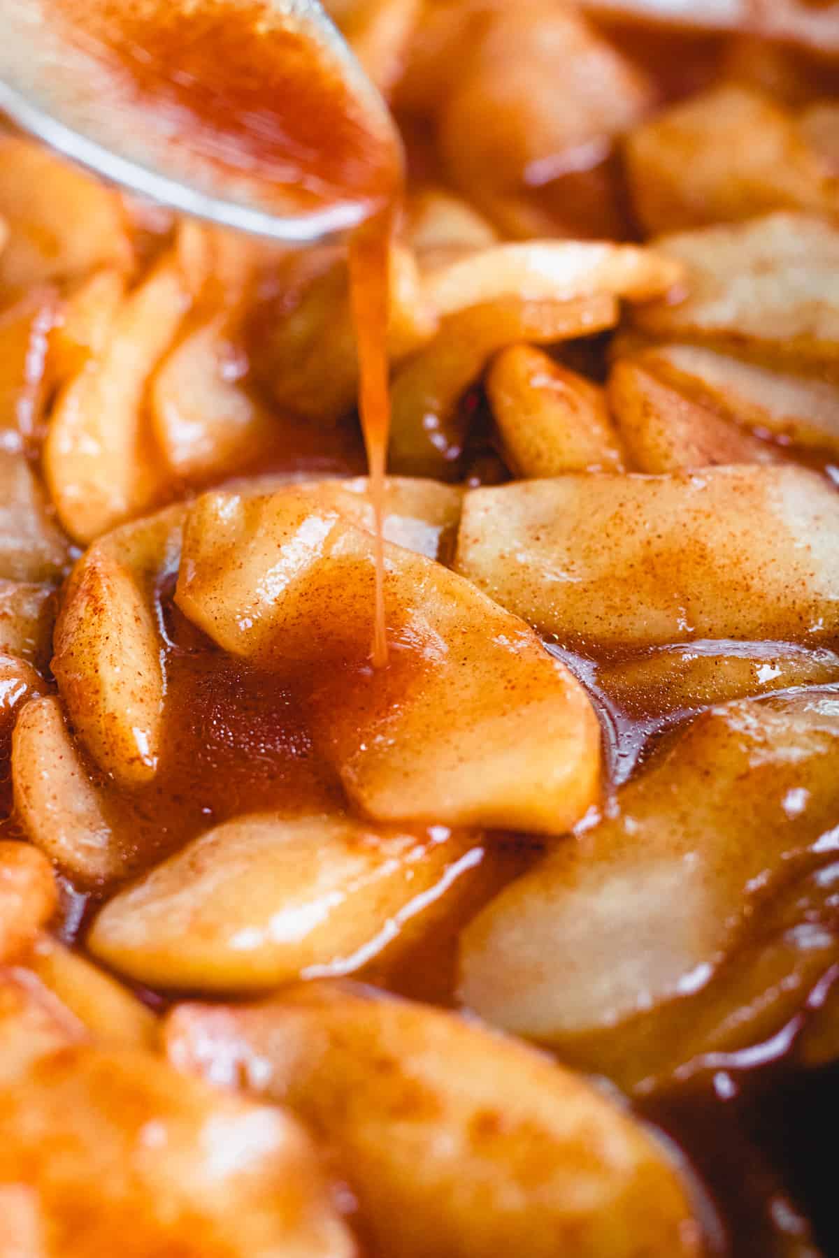 Pouring sauce over baked apple slices.