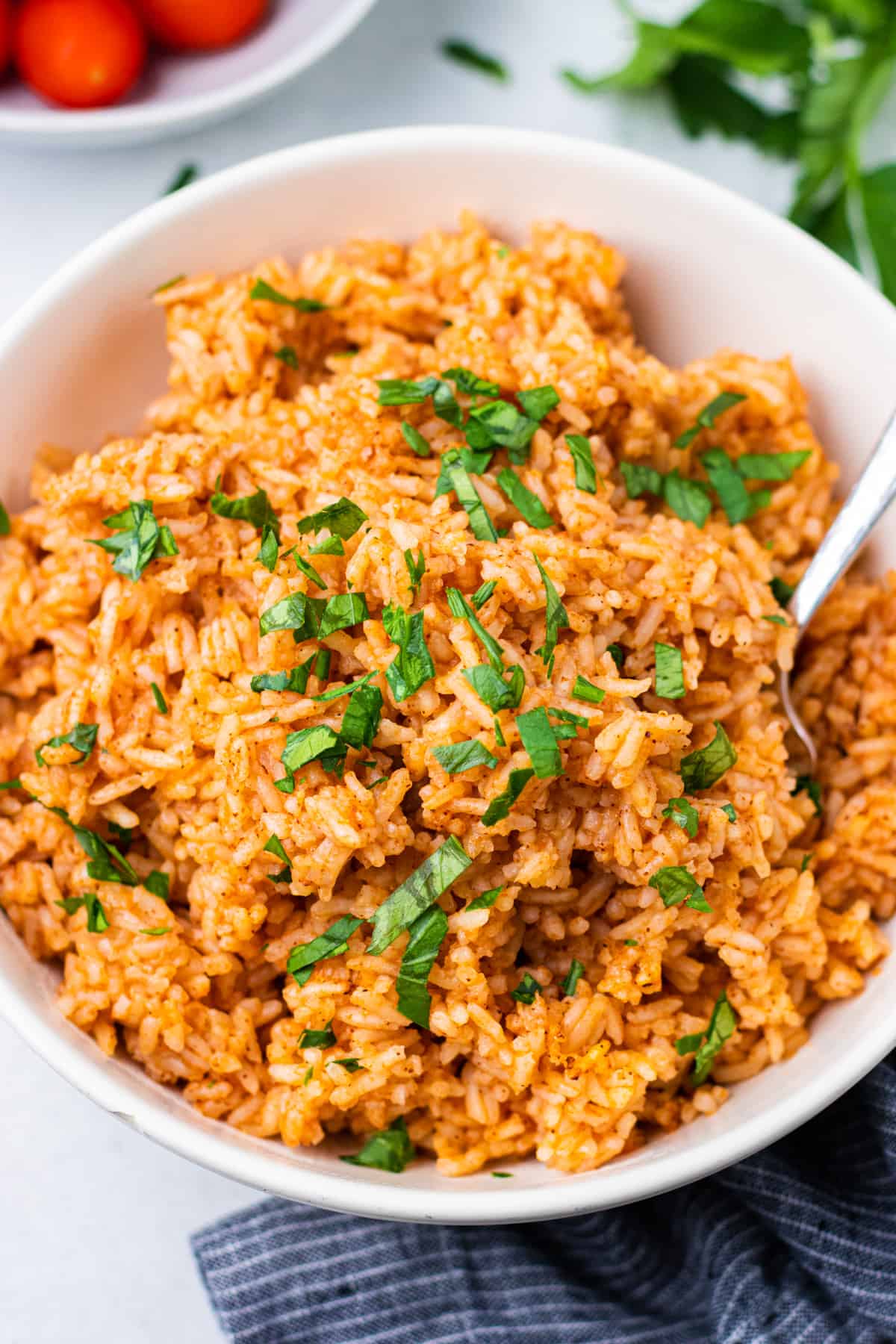 Mexican rice in a bowl with a spoon and chopped parsley.