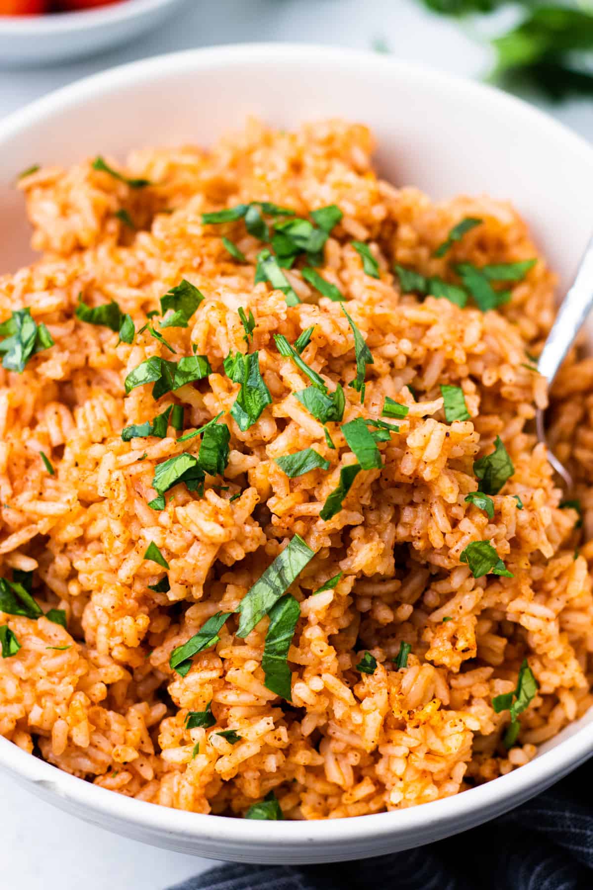 Mexican rice in a bowl with a spoon and chopped parsley.