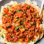 Bolognese sauce over pasta in a grey bowl.