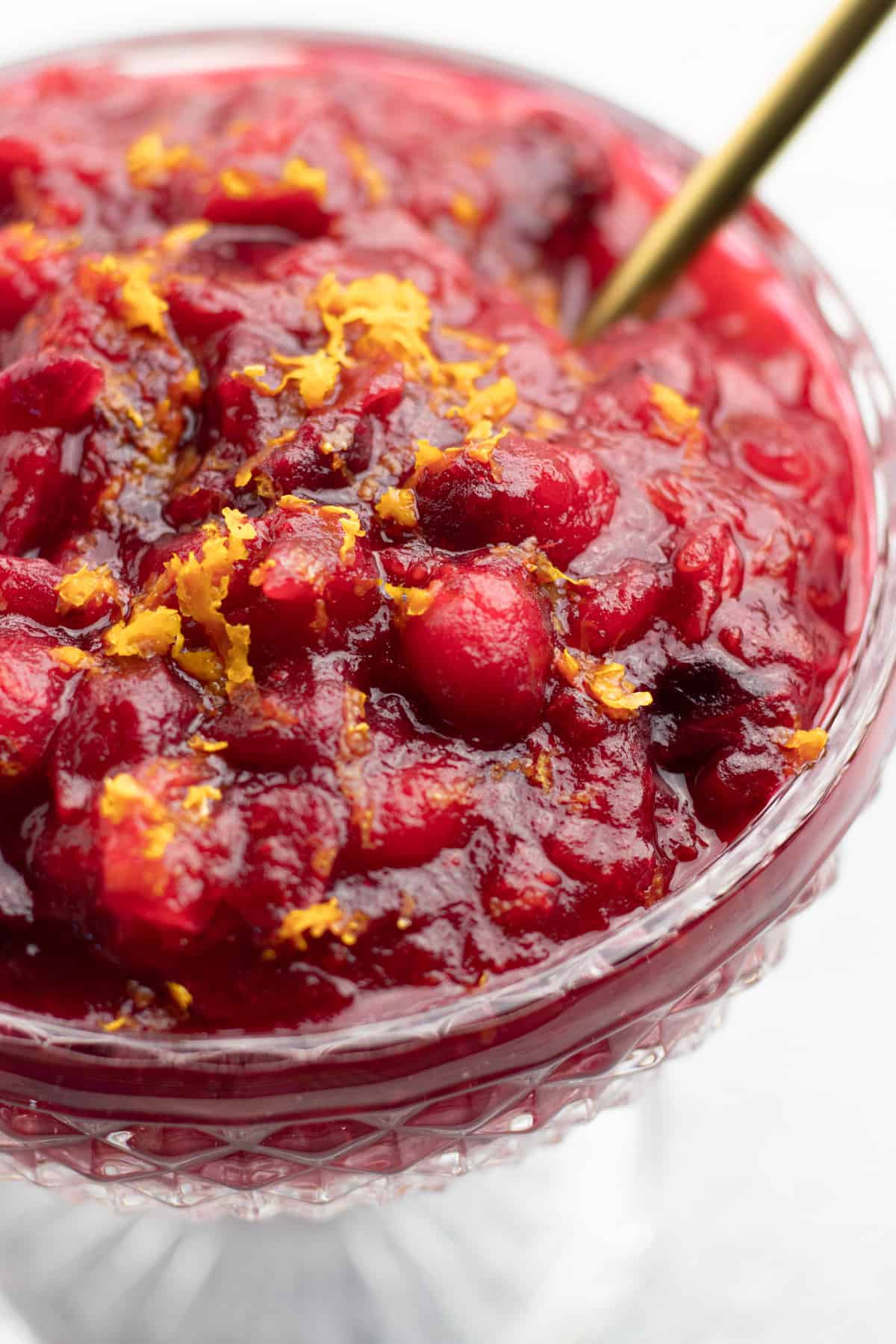 Cranberry sauce, topped with orange zest, in a glass bowl.